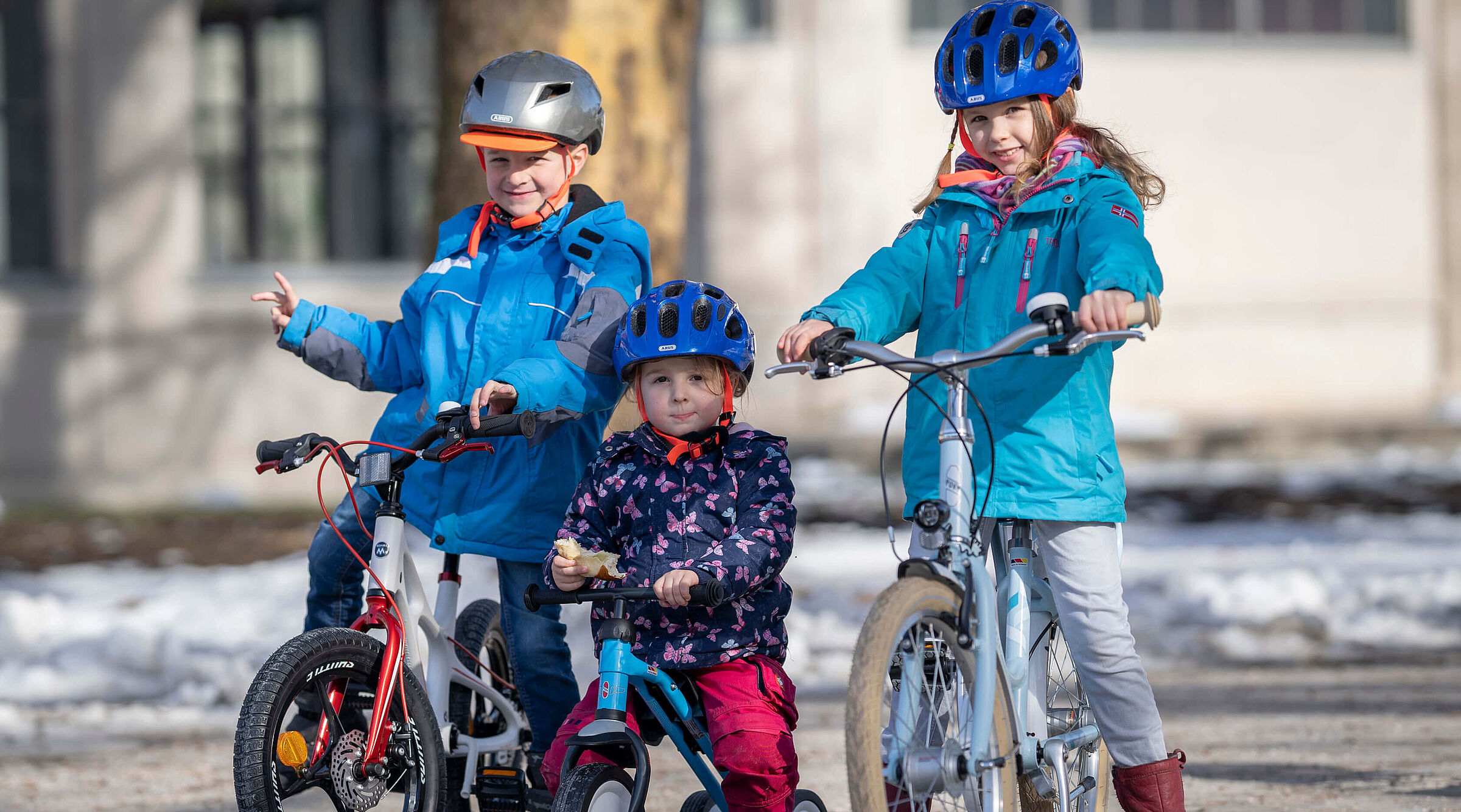 Drei Kinder in unterschiedlichem Alter auf Fahrrädern.