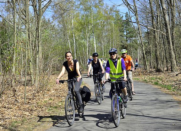 Eine Gruppe von Radfahrenden zwischen Bäumen